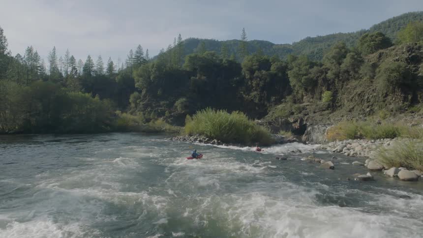 Following low behind two kayakers paddling down a fast flowing river