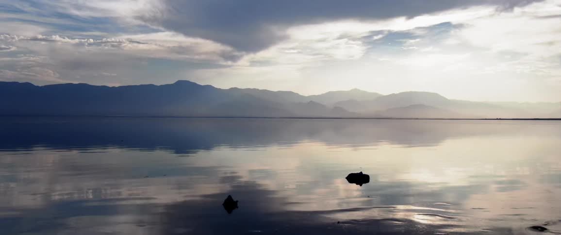Landscape facing a calm sea with mountain ranges on the horizon