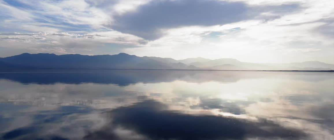 A region with a sea reflecting the sky and behind several mountains