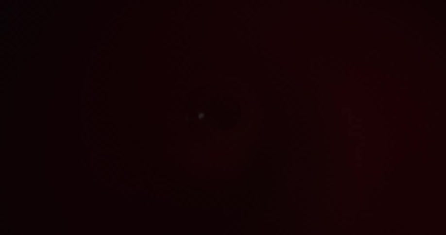 A hole is in the dark and is illuminated by a passing red light