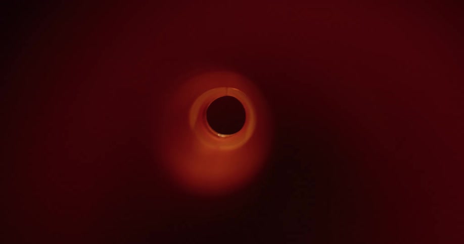 A hole is in a dark environment and is illuminated by a passing red light