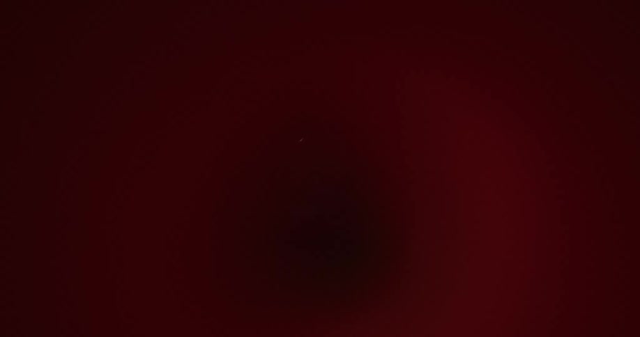 A cylindric metallic object with a round hole in the middle lit by orange lighting