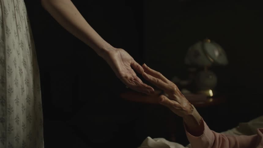 A hand of an elderly person meets a hand of skin with youthful skin