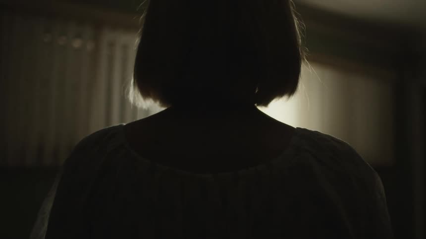 Silhouette of a person in a dark room with light passing through the window
