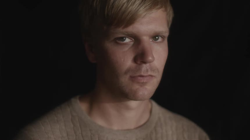 Portrait of a blond man with a neutral facial expression and sunlight reflection passing through