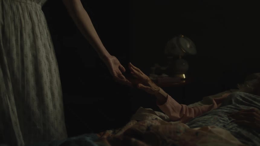 A person is holding their hand near someone in bed