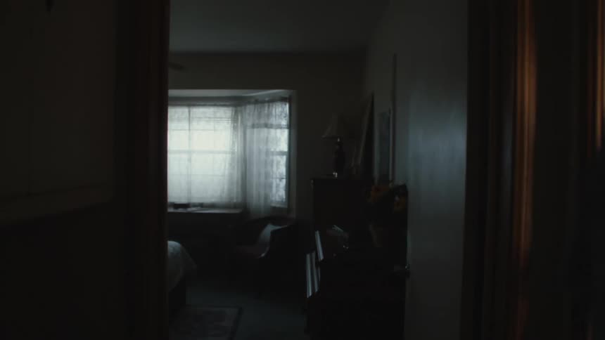 Elderly man stands in hallway looking into empty bedroom