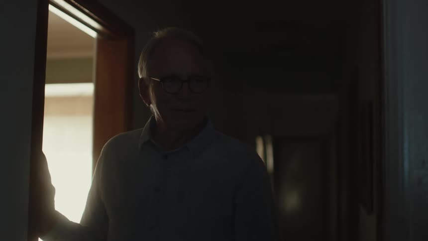 Elderly man stands in doorway with teary eyes before entering room