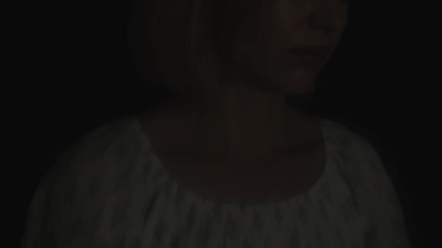 A closeup of a blonde woman wearing a white shortsleeve dress