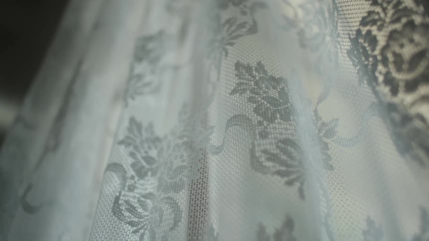Lace curtain flutters slightly in the breeze