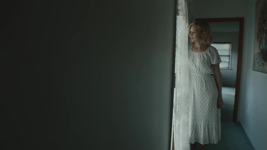 A portrait of a blonde lady standing beside the window