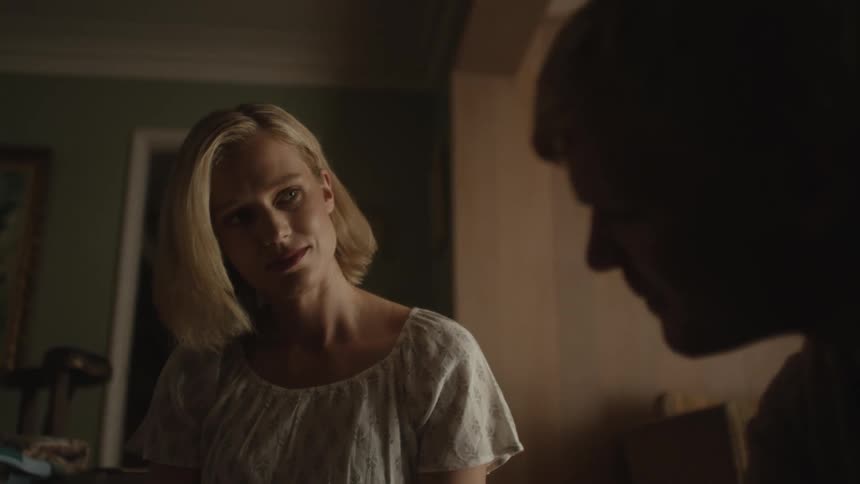 A woman smiling and watching a book together with a man and they are both sitting