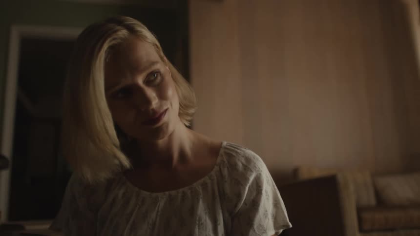 A blonde woman is reading a book to a man sitting next to her