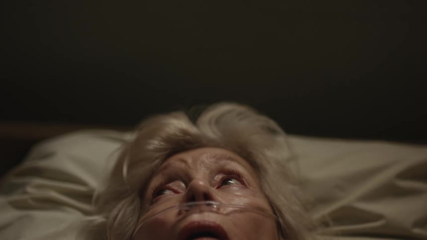 A closeup of an elderly womans face as she looks up peacefully passing away