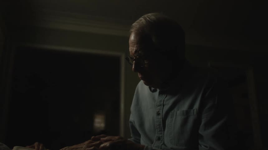 A man sitting in the dark straightening a dress