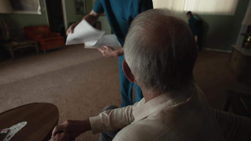 A man signing documents that a nurse gives him