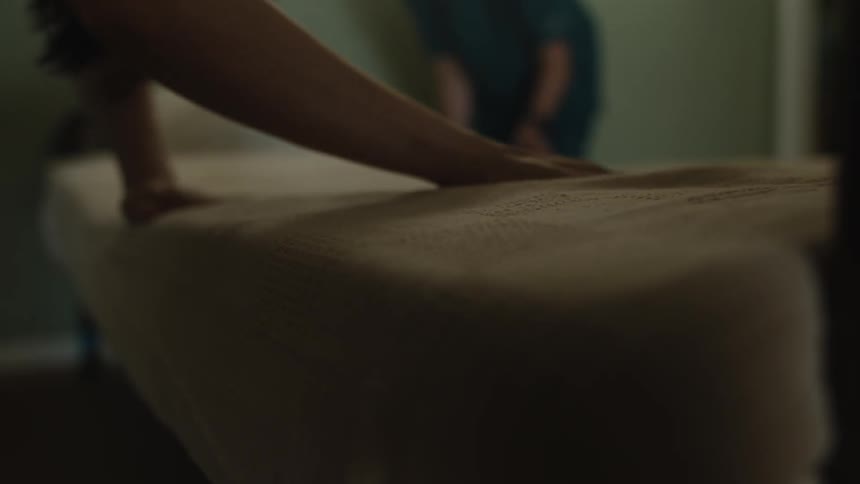 Two women are making a bed