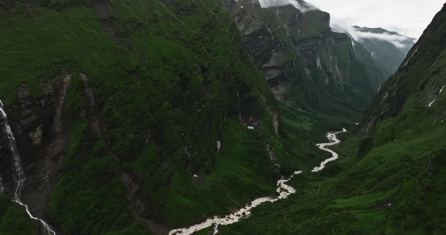 Aerial of valley with river between mountains during cloudy day