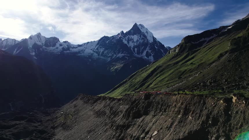 The mountain range is covered in green short grasses with a distance mountain covered in snow