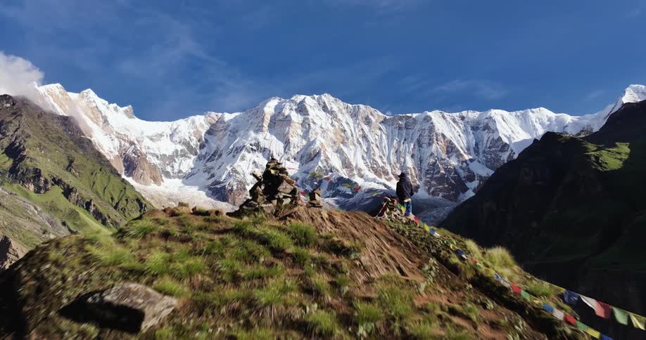A person stands on a mountaintop next to a flag banner