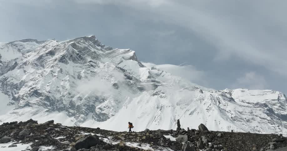 A person walking in a region with stone mountains covered in snow