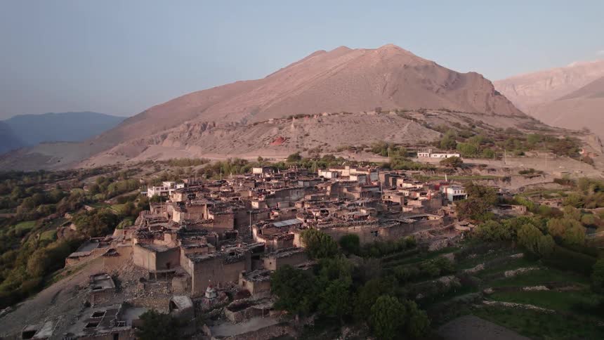 A town on top of the hill surrounded by mountains