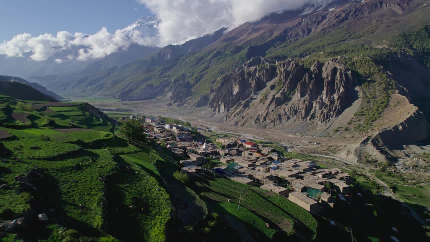 A rural region with a small village of houses and many mountains