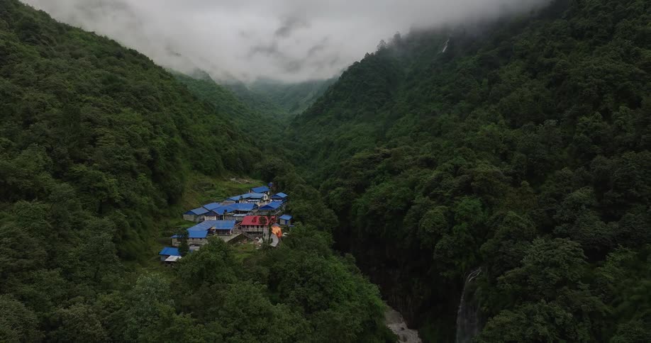 Aerial panorama of a small village nestled in the midst of mountains and surrounded by forest