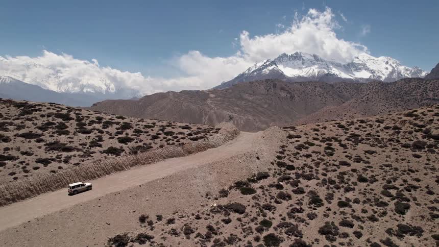 A car driving in a desert region with mountains in the background