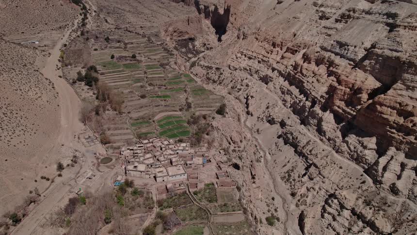 Aerial panorama of a village amidst geological mountains with snowcovered mountains on the horizon