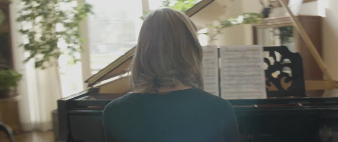 A woman is playing a large piano