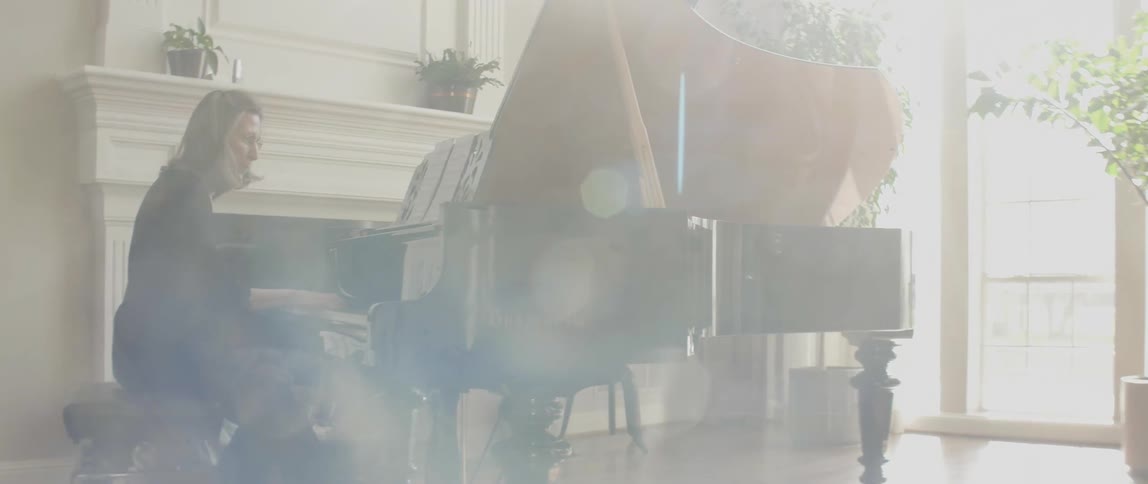 Spectacled woman playing her piano on a sunny day