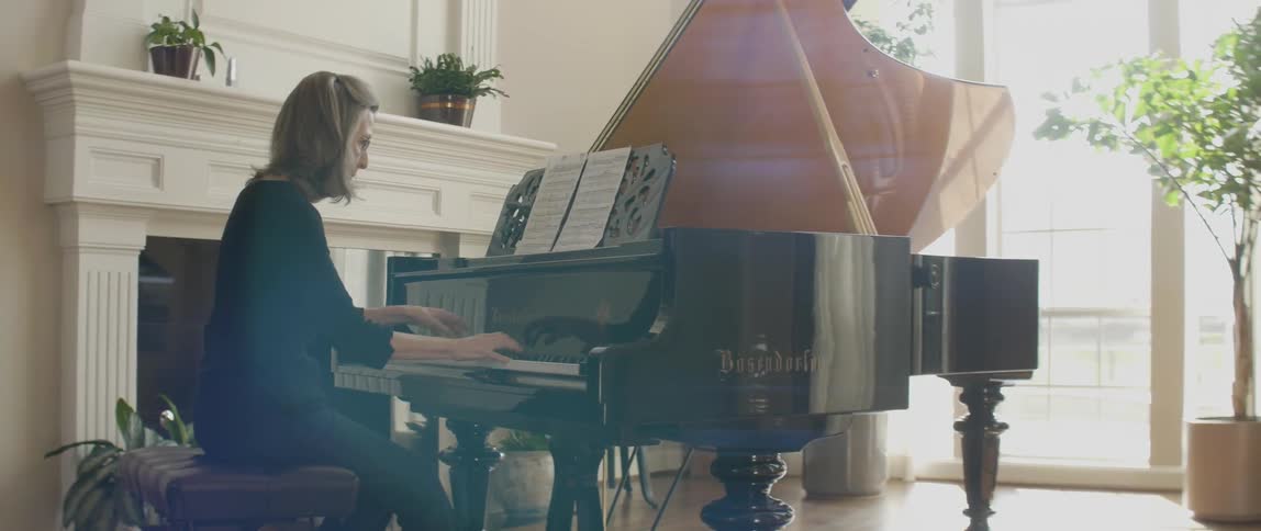 A woman is sitting playing a black piano