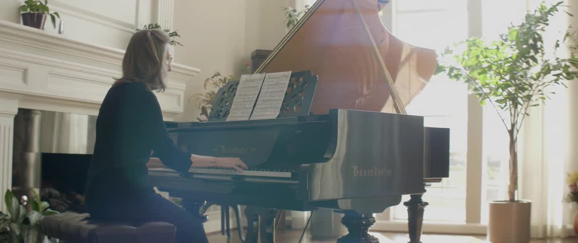 Spectacled woman playing her piano on a sunny day