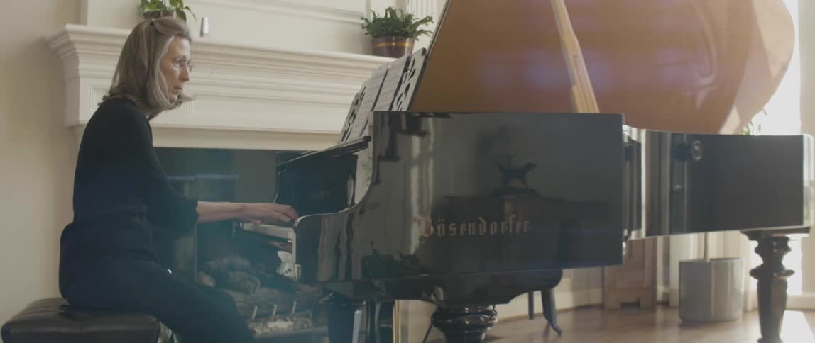 A woman is playing the piano by a chimney