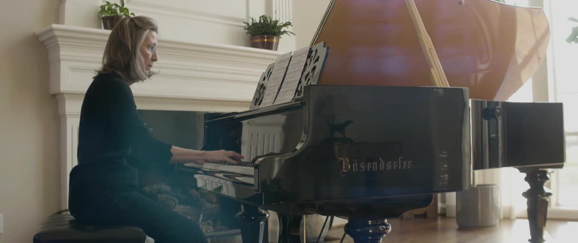 Woman plays piano and reads off of sheet music