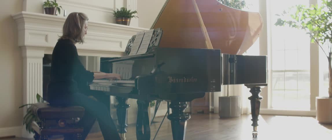 A woman is playing the piano in a brightly lit room