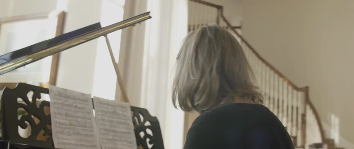 Spectacled woman playing her piano on a sunny day