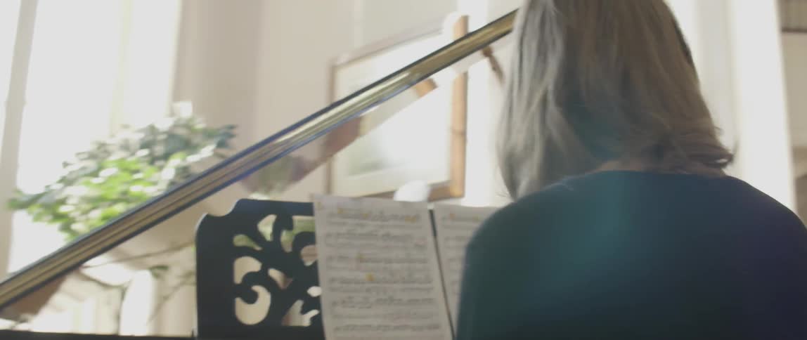 A woman is reading sheet music playing a piano