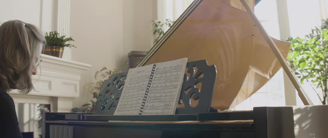 Spectacled woman playing her piano on a sunny day