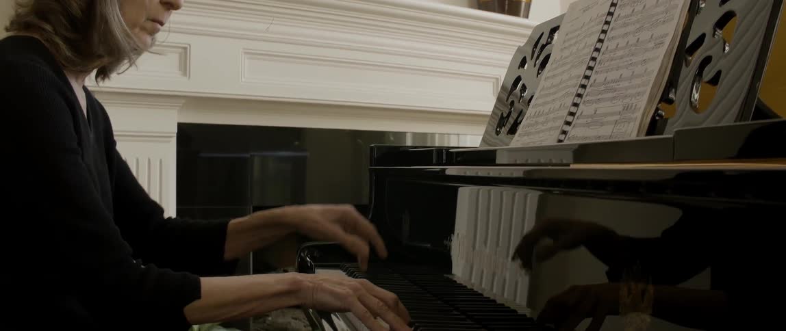 A woman is playing the piano using sheet music