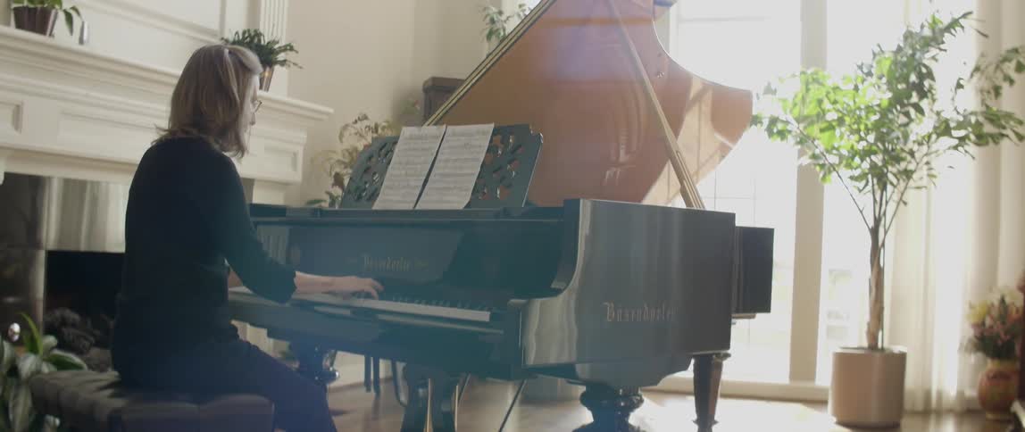 Spectacled woman playing her piano on a sunny day