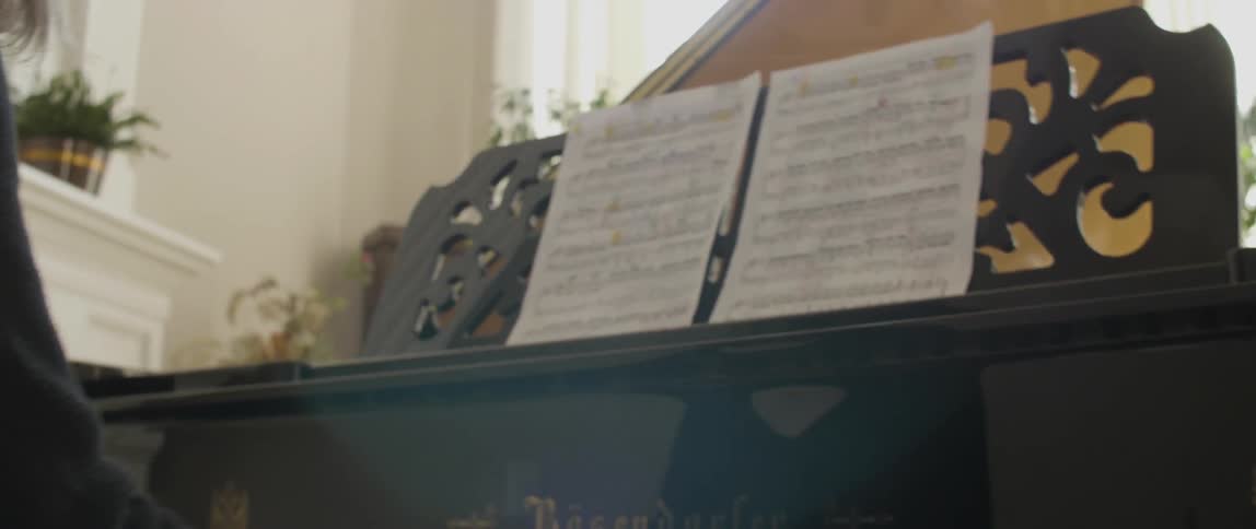A woman plays piano while looking at sheet music