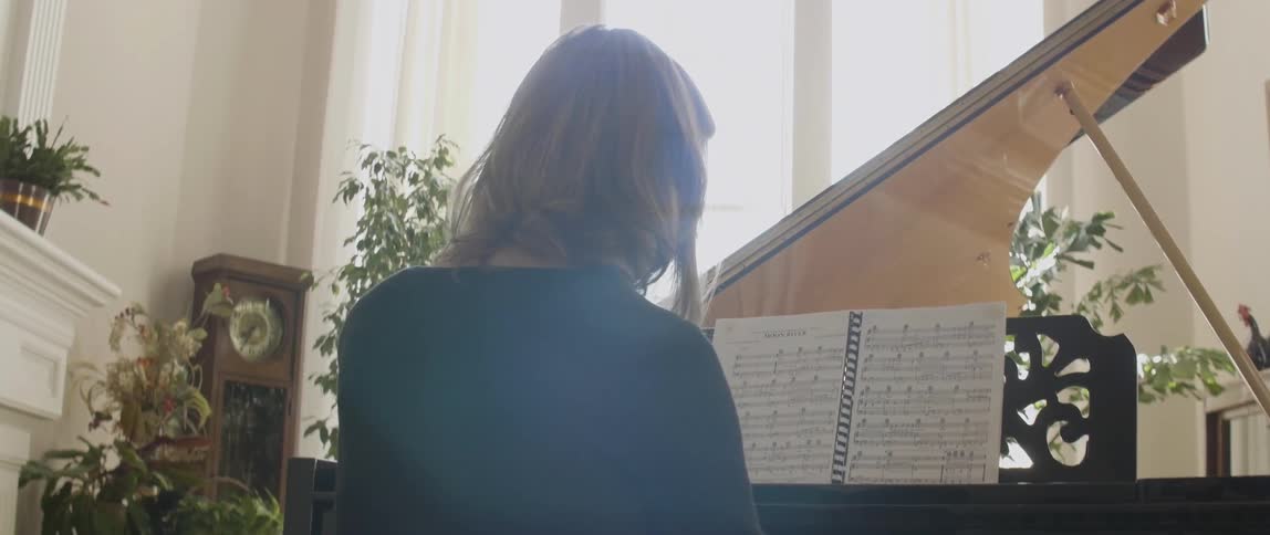 A woman is playing the piano in a bright room