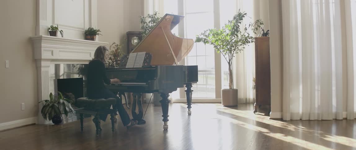 A woman is sitting at a piano playing ahead