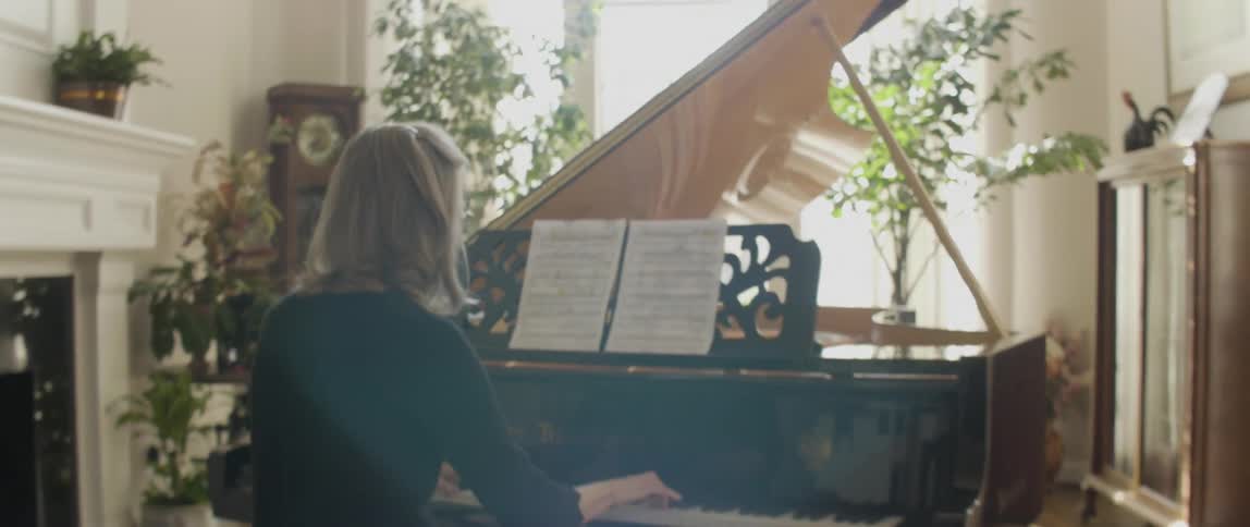 A woman is playing a piano with sheet music in front of her
