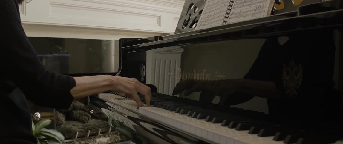 A woman is playing a piano as she leans forward