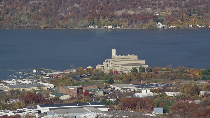 Multiple commercial buildingssit on shore across from wooded residential neighborhood during the fall