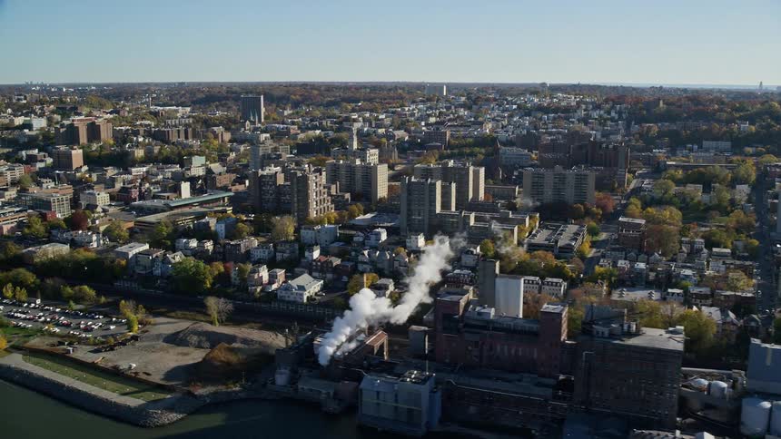 Factories and warehouses line waterfront of large town on sunny day
