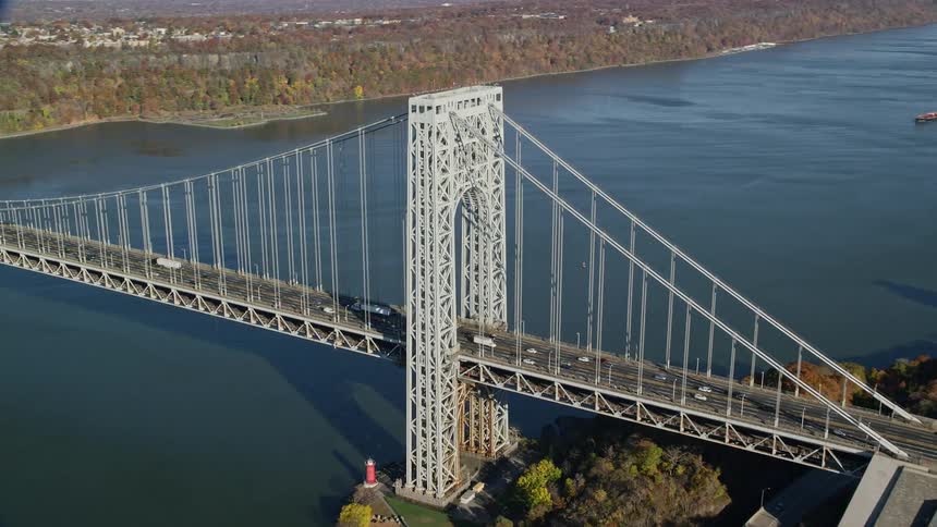 Aerial of traffic crossing suspension bridge connecting city to suburbs during fall